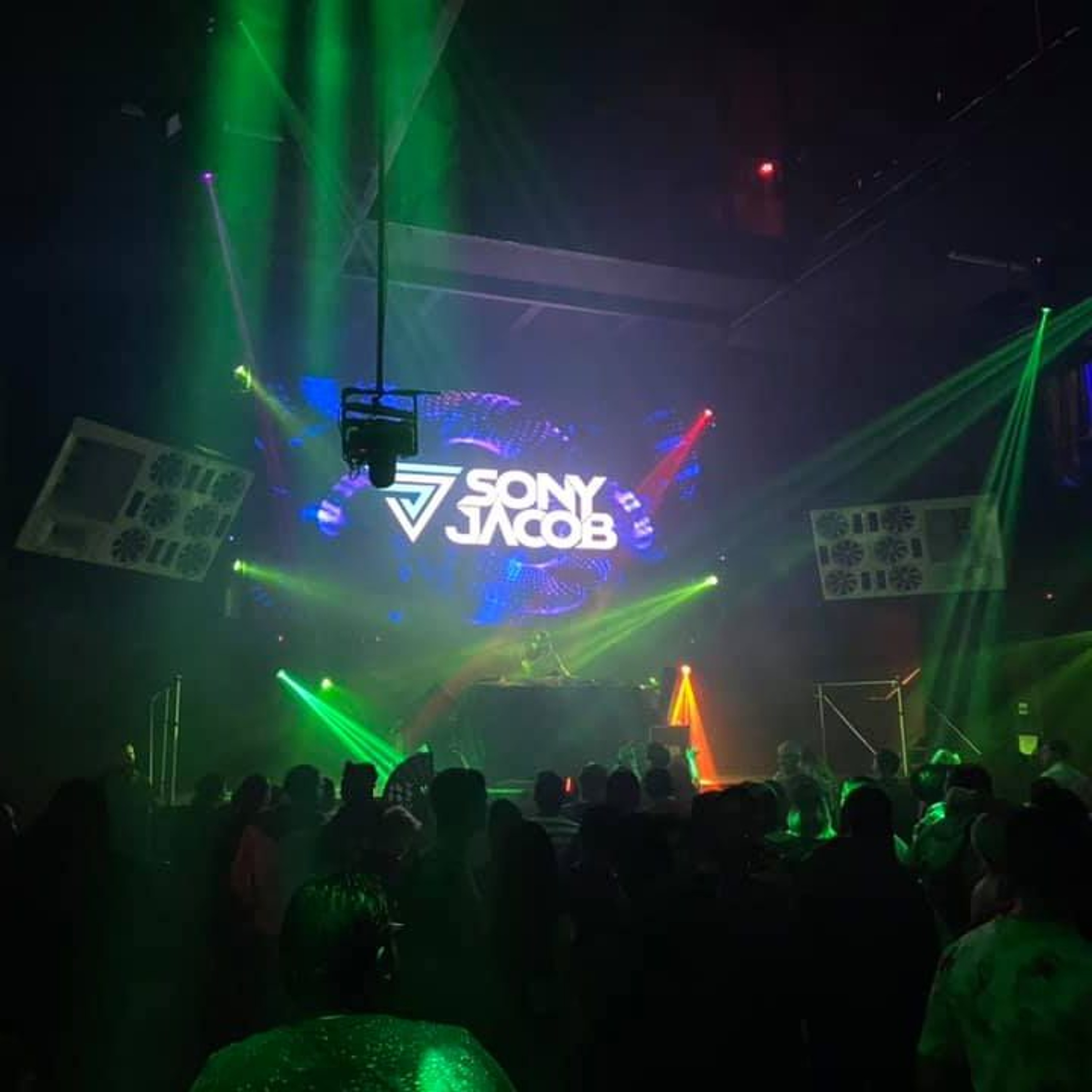 Green lights illuminate the crowd and Sony Jacob’s logo at 1015 San Francisco